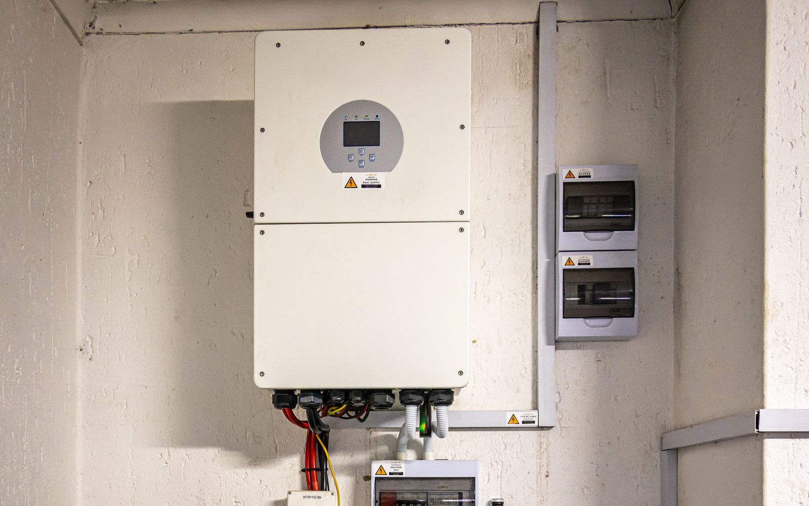 Wall-mounted home battery and inverter setup with breaker boxes