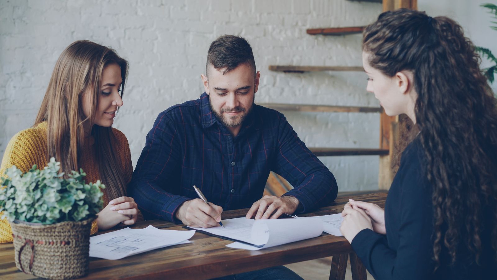 Homeowner couple reviewing paperwork with a consultant at a table
