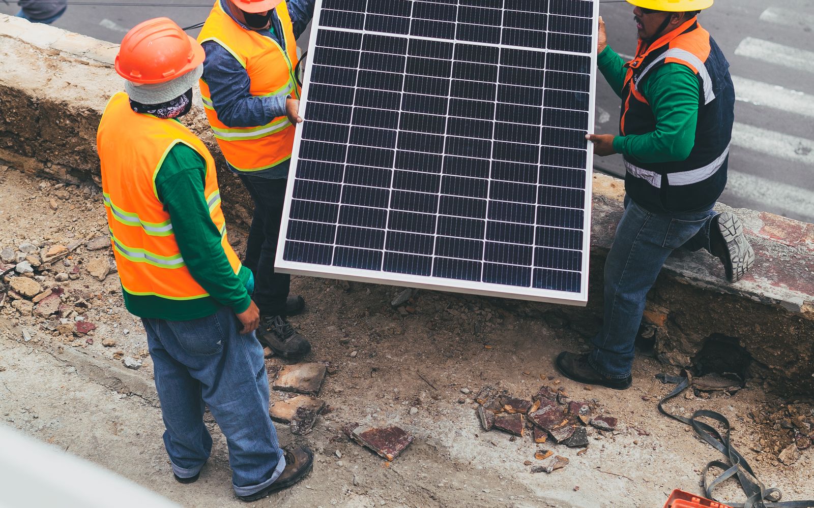 Installers carrying a solar panel across a residential rooftop