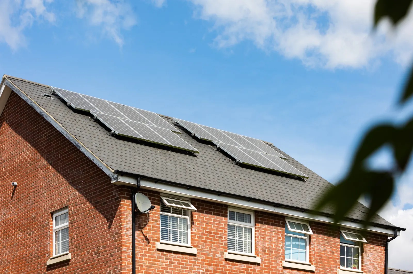 Brick suburban home with rooftop solar panels under a clear sky